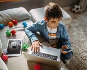 Jonge met laptop, tablet en mobiele telefoon