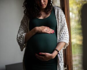 Een zwangere vrouw houdt haar buik vast